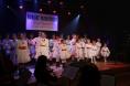 Grupa dzieci w ludowych strojach śpiewa na scenie