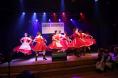 Grupa dziewczyn w ludowych sukniach tańczy na scenie